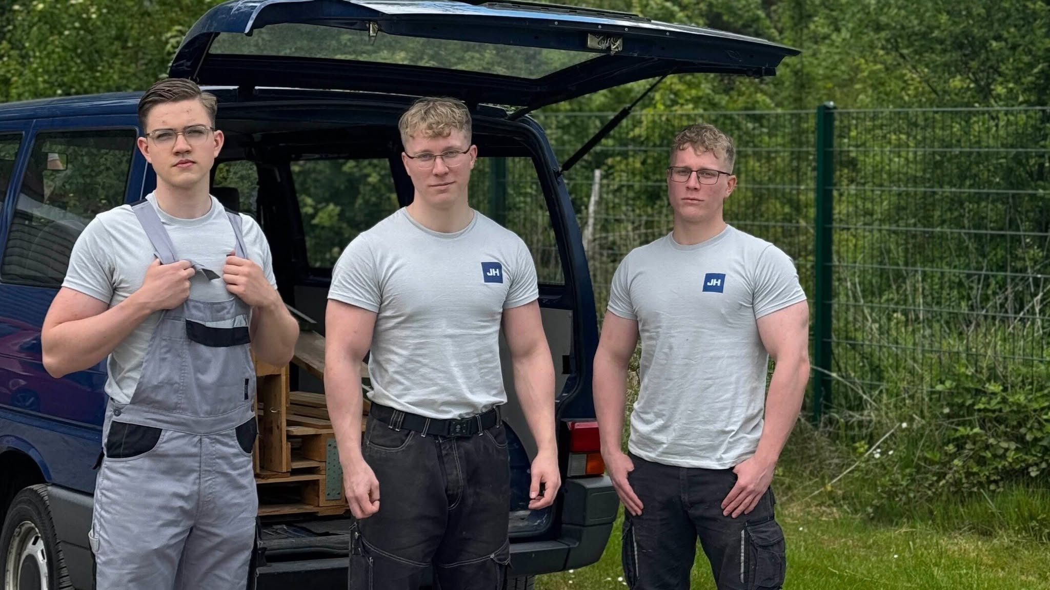 Drei Mitarbeiter von Jones & Hein in Arbeitskleidung vor dem geöffneten Transporter